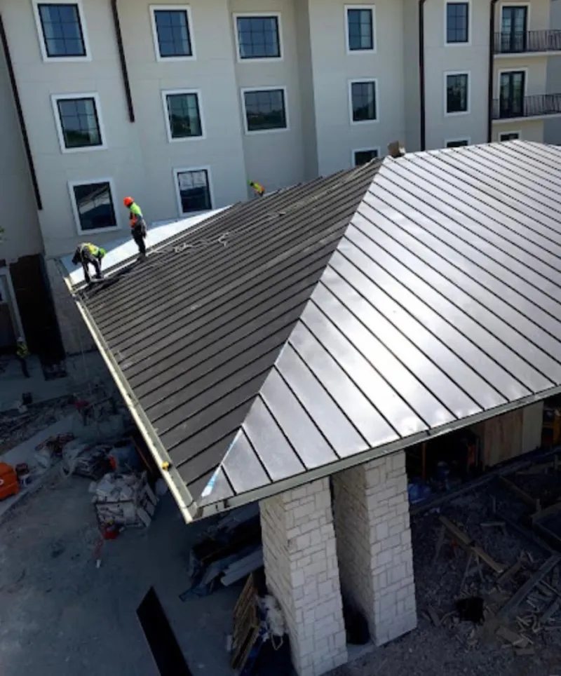 Crew installing standing seam metal roof panels on a commercial project in Clarendon Hills